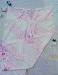 Delicate, vintage lace of pink and white trims the cuffs of these loose fitting, wide legged Palazzo pants. The crisp, white fabric has a pink floral design which harmonizes beautifully with the lace trim.A draw string waist ensures a comfortable and adjustable fit.One sizeMade in Massachusetts from 100% repurposed cotton textile and vintage lace1 of 1 Pink Lace Trim Bottoms For Spring, Pink Bottoms With Lace Trim For Spring, Spring Pink Bottoms With Lace Trim, Vintage Pink Pants For Summer, Vintage Pink Wide Leg Pants, Cotton Wide-leg Bottoms With Lace Trim, Vintage Pink Cotton Pants, Bohemian Wide-leg Bottoms With Lace Trim, Pink Stretch Vintage Bottoms