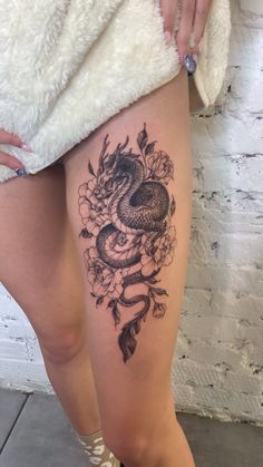 a woman's thigh with a snake and flowers tattoo on the side of her leg