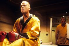 two men in yellow shirts and red boxing gloves, one is sitting on the floor