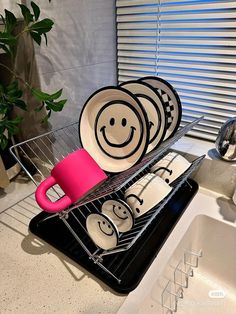 a rack with plates and cups in it on the counter next to a kitchen sink