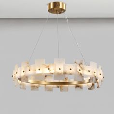 a chandelier made out of white marble blocks hanging from a gold ceiling fixture