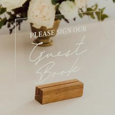 a clear acrylic sign sitting on top of a table next to a vase filled with flowers