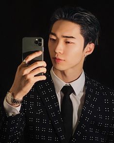 a man in a suit taking a selfie with his cell phone