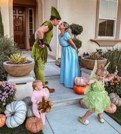 two children and an adult dressed as tinkerbells kissing in front of a house