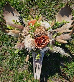 an arrangement of flowers and feathers on the ground with grass in the backround