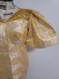 the back of a dress with gold brocades on it and a white background