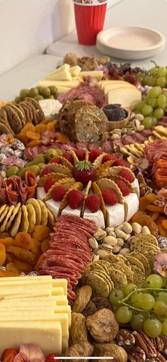 an assortment of cheeses, fruits and nuts on a platter