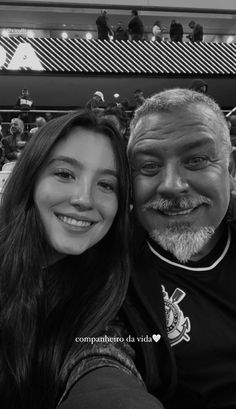 a man and woman taking a selfie in front of an audience at a sporting event