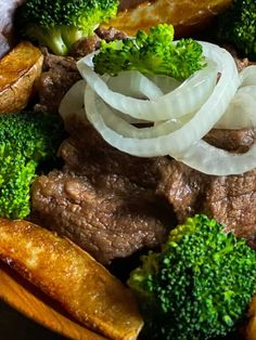 beef, onions and broccoli in a bowl with potatoes on the side for garnish