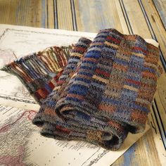 two knitted scarves sitting on top of an old map