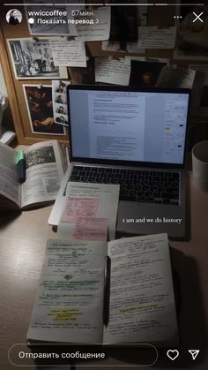 an open laptop computer sitting on top of a wooden desk next to papers and pictures