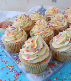 cupcakes with white frosting and sprinkles on a tray