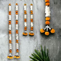 four orange and white flowers are arranged on a table next to two silver vases