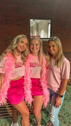 three girls in pink cheerleader outfits posing for the camera