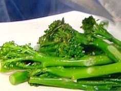 some broccoli sitting on top of a white plate next to other green vegetables