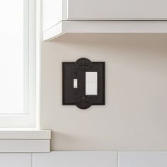 a black light switch on the wall in a kitchen with white cabinets and counter tops