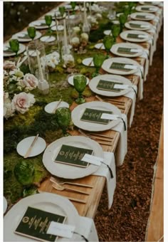 a long table is set with white plates and place settings for the guests to eat