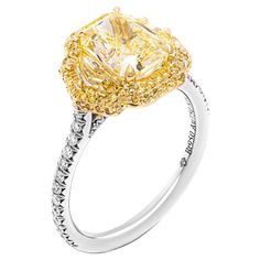 a fancy yellow diamond ring with white and yellow diamonds on the sides, set in 18k gold