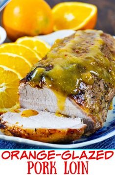 an orange glazed pork loin on a plate with sliced oranges and gravy