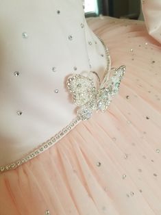 a pink dress with a butterfly brooch on it