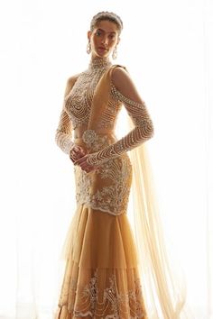 Beige mermaid silhouette layered lehenga saree with astron bloom embroidery using pearls, bugle beads, crystals, sequins, aari highlights. Paired with a halter neck blouse with all over Royal pearl crystal embellishments and long cold shoulder sleeves detailing. - Aza Fashions Fitted Evening Dress With Traditional Drape, Festive Reception Dress With Sheer Sleeves, Floor-length Dresses With Sheer Sleeves For Reception, Traditional Drape Embellished Evening Dress For Reception, Embellished Evening Dress For Reception With Traditional Drape, Festive Evening Dress With Traditional Drape For Receptions, Festive Traditional Drape Evening Dress For Receptions, Glamorous Semi-stitched Dress With Sheer Dupatta, Floor-length Evening Dress With Sheer Dupatta For Wedding