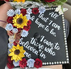 a graduation cap decorated with flowers and writing on the front is being held in someone's lap