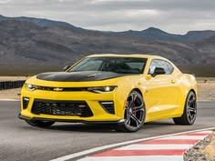 a yellow chevrolet camaro is driving down the road