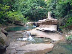 there is a small stream in the middle of some rocks and trees on either side