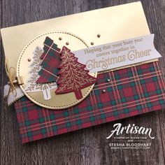 a christmas card made with plaid paper and gold trimmings on a wooden table