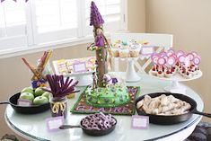 a table topped with cakes and cupcakes next to a cake plate filled with cookies