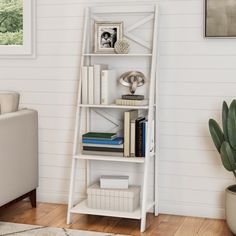 a white book shelf with books and pictures on it in the corner of a living room