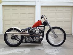 a red and black motorcycle parked in front of a garage