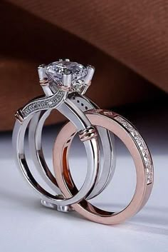 two wedding rings with diamond accents on each one and an engagement ring in the middle