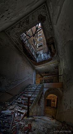 an abandoned building with stairs leading up to the second floor and skylight above it