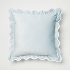 a light blue pillow with scalloped edges on a white background, top view