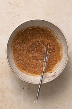 a bowl filled with spices next to a whisk