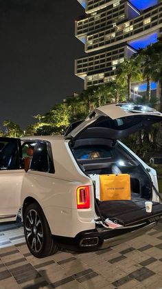 two white cars parked next to each other on a checkered floor in front of tall buildings