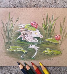 some colored pencils are laying on the ground next to a drawing of a dragon