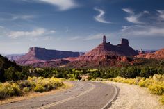 an empty road in the desert with mountains in the background