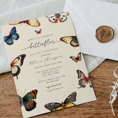 a close up of a card on a table with a envelope and some butterfly decorations