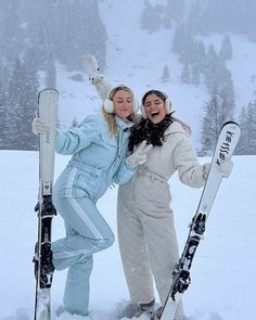 two women standing in the snow with their skis