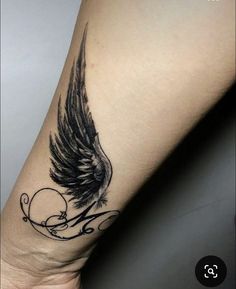 a black and white tattoo on the arm of a woman's leg with an angel wing