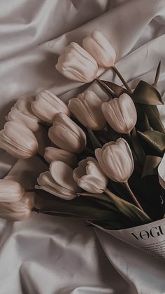 a bouquet of white tulips sitting on top of a bed