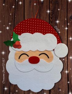 a paper santa claus face hanging on a wooden background with stars and snowflakes