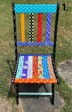 a colorful chair sitting on top of a grass covered field