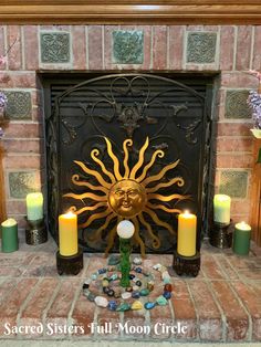 a fire place with candles, rocks and a sun decoration