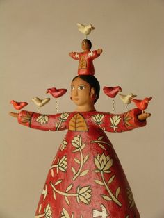 a red figurine with birds on it's head and arms spread out