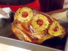 a pan filled with pineapples and other food on top of a counter next to a person