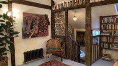 a living room filled with furniture and bookshelves next to a doorway that leads to a second story