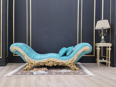 a blue chaise lounge sitting on top of a wooden floor next to a lamp